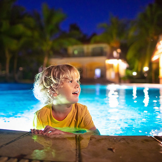 Child coming out of pool on edge in nightttime