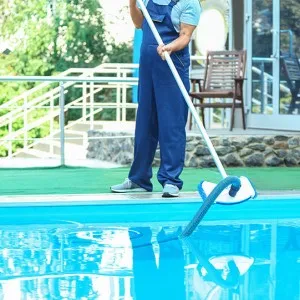 Man holding pool vacuum doing maintenance